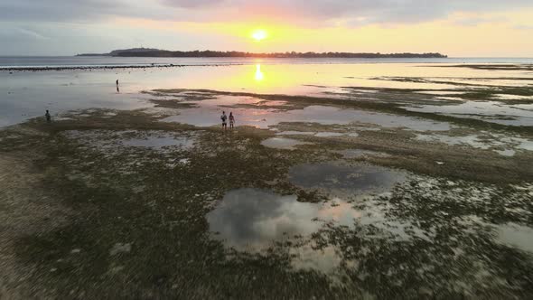 Aerial flyover paradise landscape,walking couple and water reflection during sunset at horizon. alt