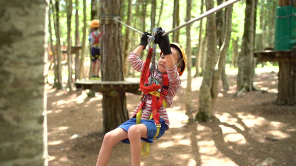 Boy Moves with the Help of His Hands on the Zip Line in the Adventure Park alt