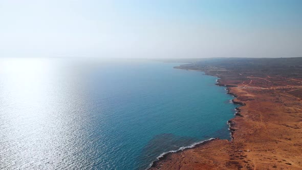 Aerial shot flying over the rocky coast of Cavo Greko in Cyprus alt