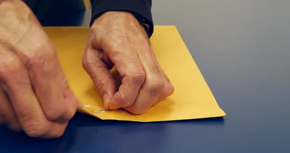 Close up on hands opening an orange envelope with important document inside after being mailed and d alt