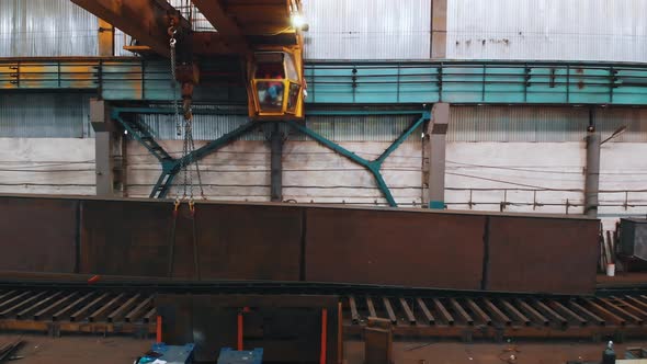 Plant for the Construction of Cranes - Man Controlling the Crane Lifting the Oblong Manufactured alt