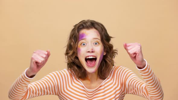 Portrait of Emotional Woman 20s with Colorful Designer Painting on Face Shouting and Clenching Fists alt