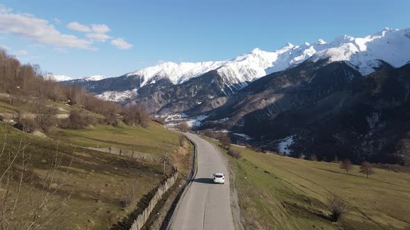 Drone aerial view. Car on the road between mountains. Caucasus, Georgia and Sunny weather. alt