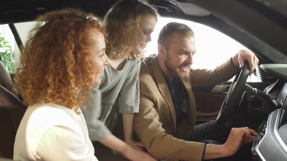 Young Caucasian Couple Sit Inside of New Car in Dealership alt