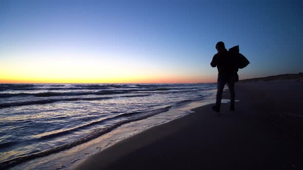 Traveler Silhouette Walking Along Sea At Dusk