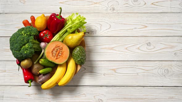 Plate with vegetables and fruits on wooden table. Healthy food. Top View. Stop Motion