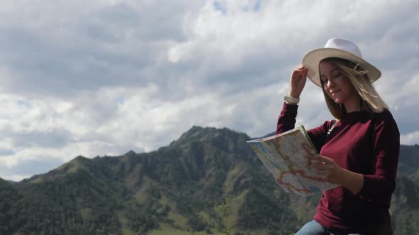 Woman Traveler Hiker Sitting on Top of Rocky Mountains Learning Route on Map