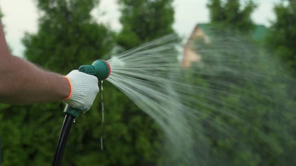 Gardening and Maintainance Close Up of Man Hands with Hose Watering the Lawn alt