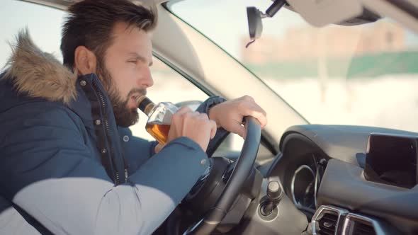 Drunken Driving Risk Car Accident.Man Holding Alcohol Bottle In Car. Dangerous On Road Drunk Driving alt