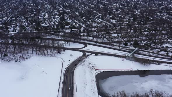 An aerial view from a drone, over a cleared road with a frozen lake on either side. It was during a alt