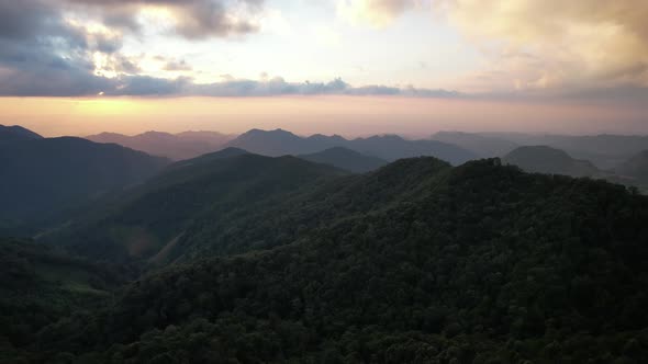 Aerial landscape view of greenery rainforest mountains before sunset by drone