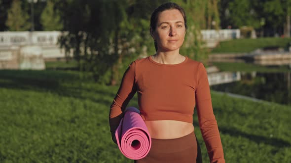 Woman walking with fitness mat in park
