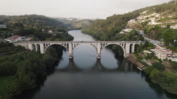 Aerial orbiting view Cars crossing Entre-os-Rios bridge over idyllic Tamega river