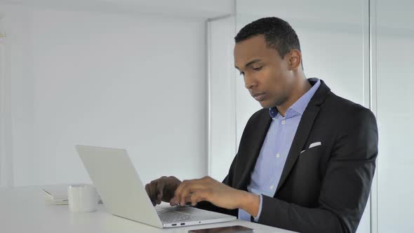 Pensive Casual AfroAmerican Businessman Thinking and Working on Laptop alt