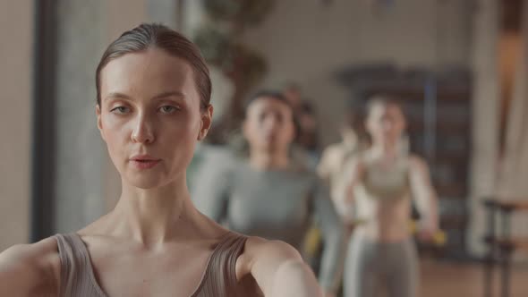 Young Woman Doing Dumbbell Front Raise during Workout alt