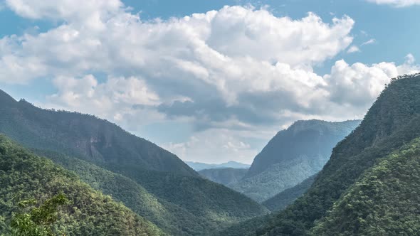 Timelapse of Clouds Moving Above Mountain Valley on Sunny Day alt