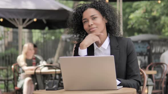 Thinking Happy African Woman Working on Laptop Outdoor Cafe alt