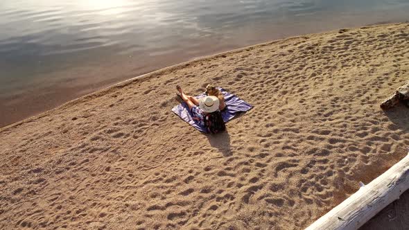 Woman with her pet dog sitting near the river coast on a sunny day 4K 4k alt