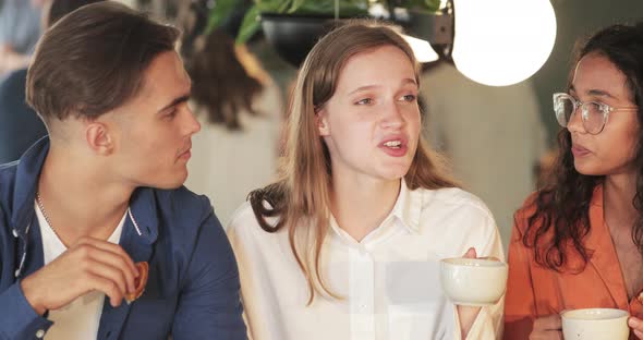 Young Attractive Girl Telling Funny Story To Friends While They Having Good Time in Cafe. Millennial alt