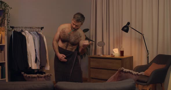 Good Looking Mature Guy in Bath Towel Pretending Playing Guitar While Brushing Teeth, Emotional alt