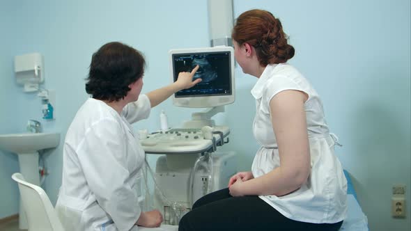 Female Doctor Showing Ultrasound Results To Woman Patient in Clinic alt