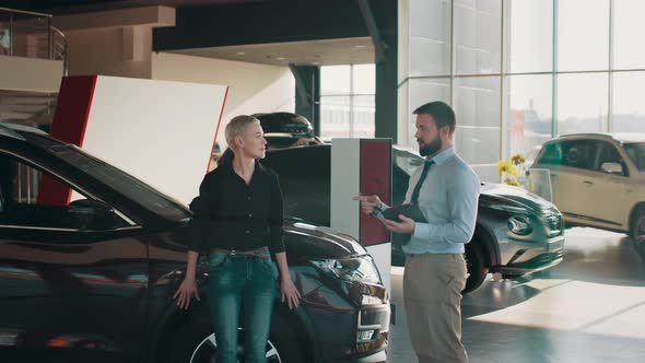 Handsome Man Competent Car Dealer Using Digital Tablet for Work with Clients at alt
