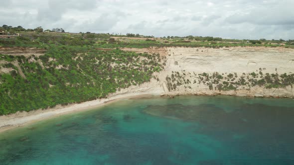 AERIAL: Greenery on Slope in Il-Hofra l-Kbira Bay with Turquoise Colour Water