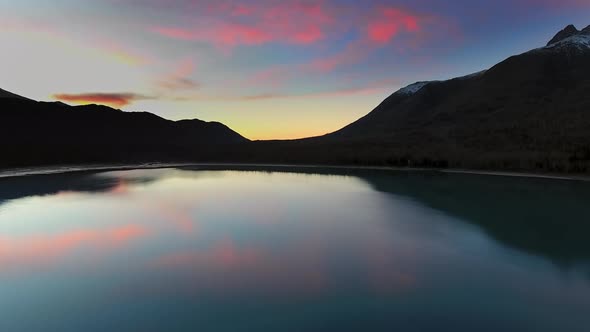 Drone capture magenta sunset in lake with forest and mountain in Eklutna Lake, Alaska, USA alt