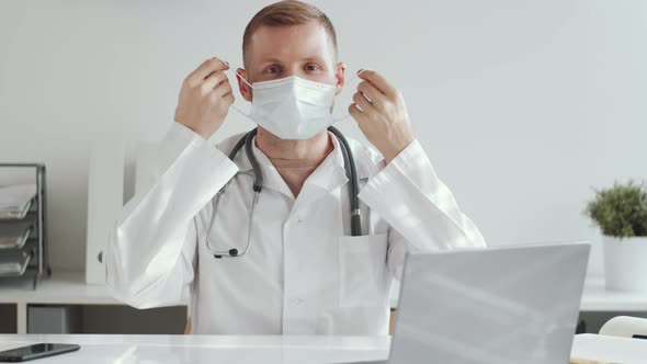 Male Doctor Taking off Face Mask and Smiling at Camera alt