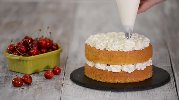 Decorating a Cherry Cake with Cream From the Pastry Bag alt