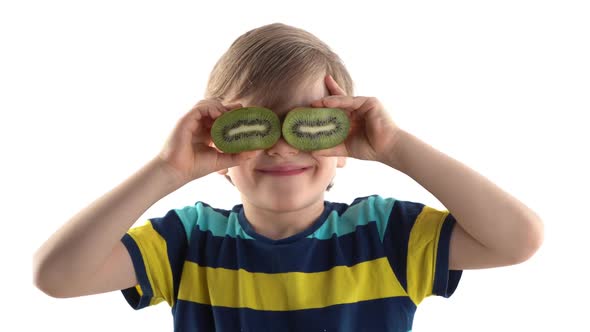 Little Boy Posing in Studio on a White Background with Cut Kiwi Instead of Eyes