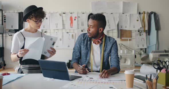 Male Tailor Drawing Clothes Using Laptop When Young Woman Coming with Sketches alt