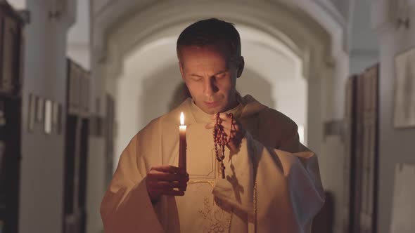 Priest Blowing Out Candle after Praying alt