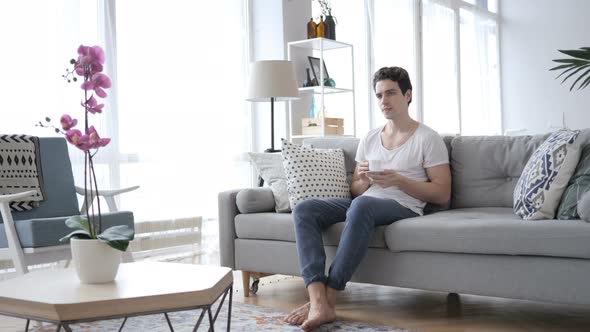 Man Drinking Coffee While Sitting On Sofa At Home By Stockland Man Drinking Coffee While Sitting On Sofa At Home Stock Footage