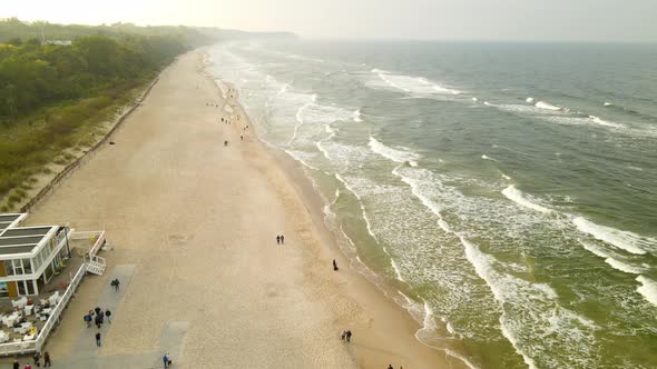 Beach Pullback Aerial Drone Over Cold Families Enjoying Gloomy Evening at Wladyslawowo Beach, Poland alt