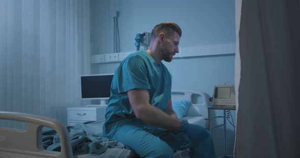 Upset Doctor Turning Off Medical Equipment Sitting on Empty Stretcher Bed alt