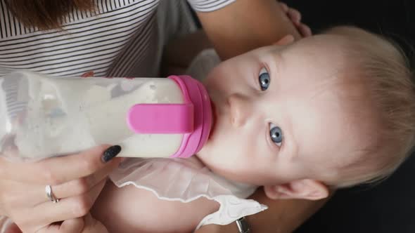 Young Mother Feeding Baby Drinking From Milk Bottle