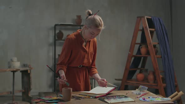 Female Painter Drawing in Sketchbook with Watercolors alt