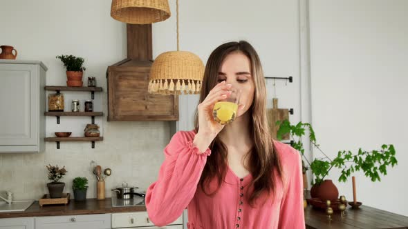Girl With Braces Drinks Juice In The Kitchen And Smiles