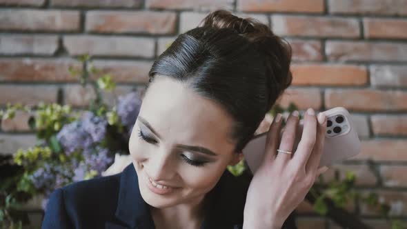 Young Woman Holding the Phone to Her Ear Listens to a Voice Message While Sitting on the Couch alt