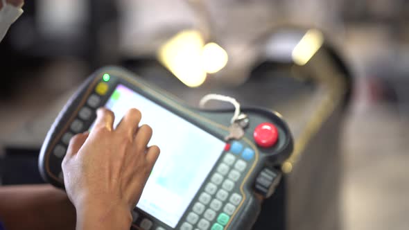 Close-up on A male worker hand is controlling a welding robot. alt