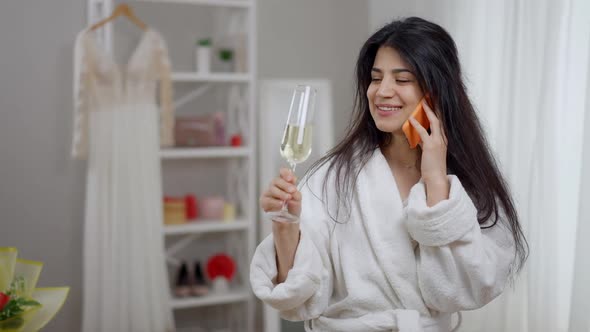 Camera Approaches to Joyful Laughing Modern Middle Eastern Bride Talking on the Phone Drinking alt