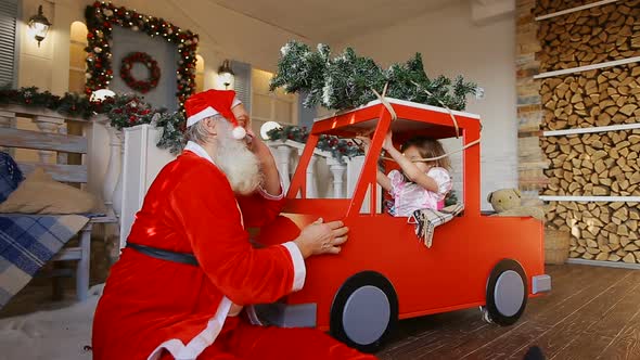 Santa Claus Talking on Phone and Plays with Little Girl