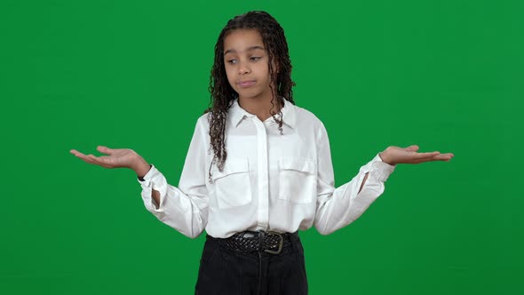 Unsure Puzzled African American Teen Girl Holding Invisible on Green Screen Shrugging Shoulders alt