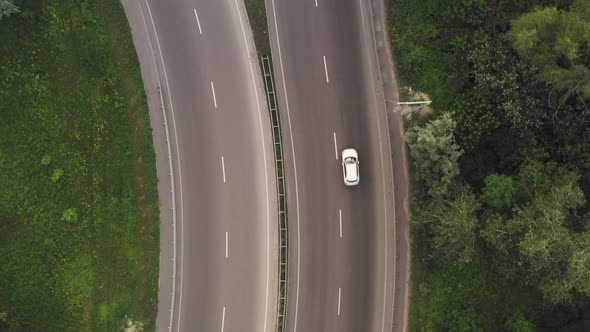 Cars and Trucks Move Along the Lanes of the Highway Among the Green Foliage alt