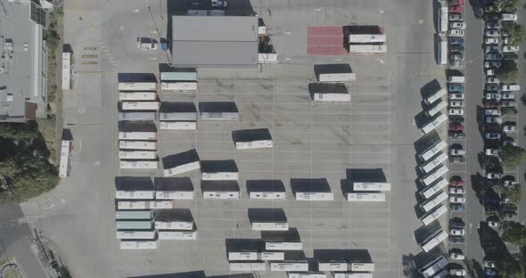 Static aerial perspective looking down over how bus depot is organized while one machine navigates t alt