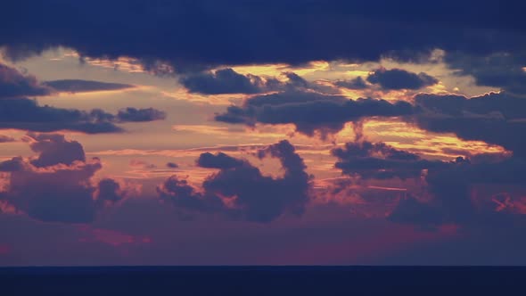 Bright Disk of Sun Moves Through Gapes of Clouds in Shining Sunset Sky alt