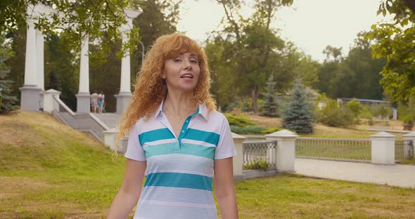 Happy Cool Blondehaired Woman Wearing Headphones Dancing Alone in a Park at Sunset alt