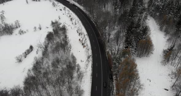 Aerial, tilt up, drone shot, of a wet road, in Romanian highlands, bad weather, on a overcast, winte alt