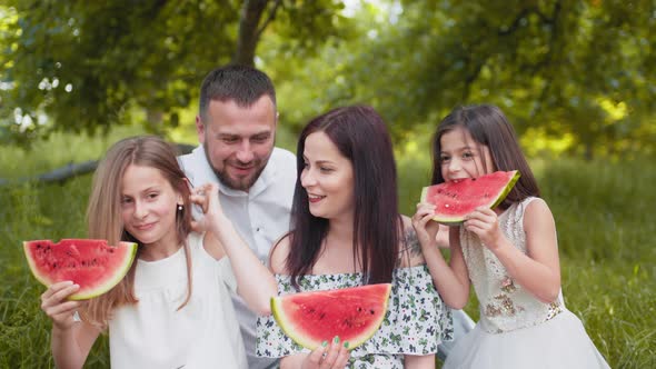 Joyful Caucasian Family with Two Little Daughters Eating Watermelon Outdoors alt